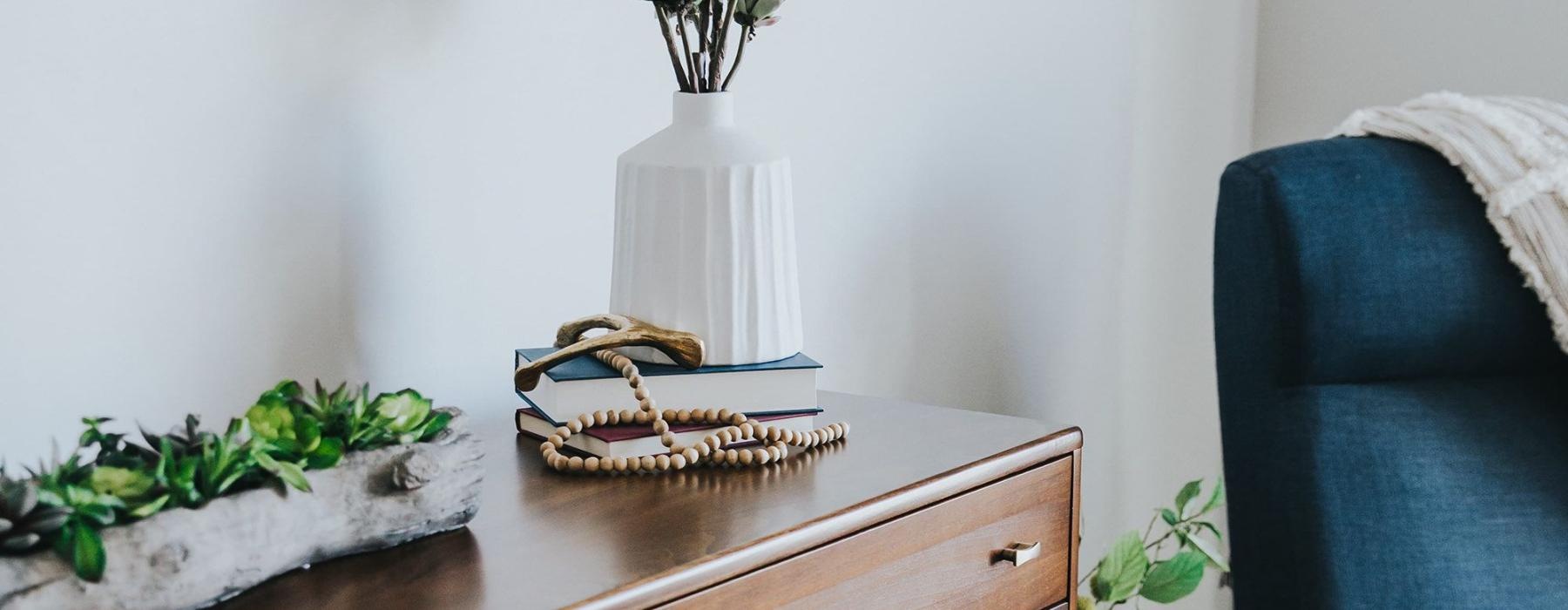 a dresser with a vase of plants on top